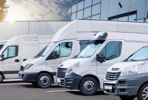Fleet of white commercial vans parked in a row outside a modern building