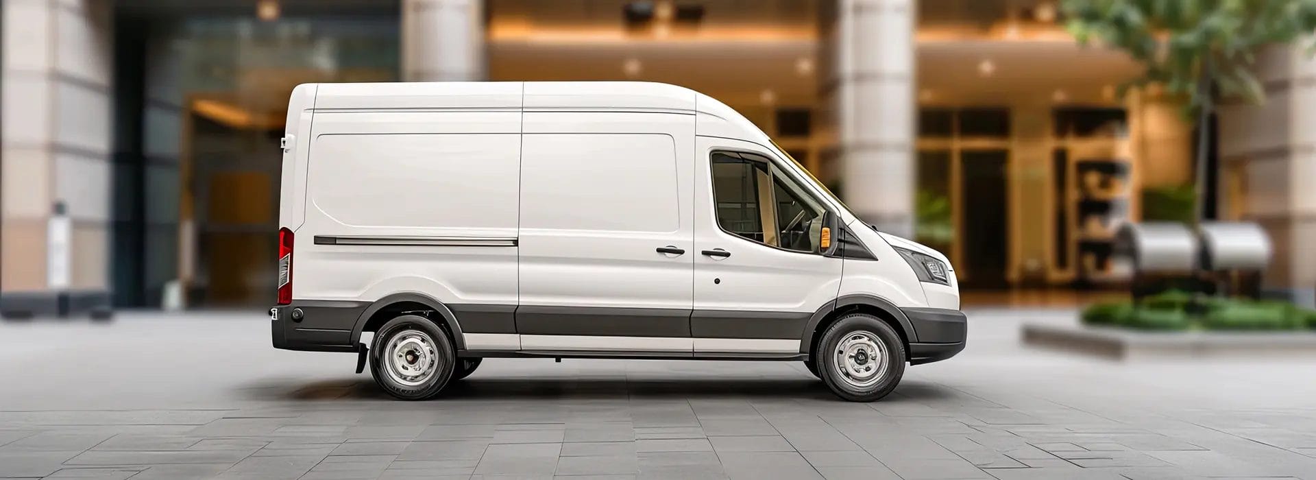 White Ford Transit van parked outside a modern building on a city street
