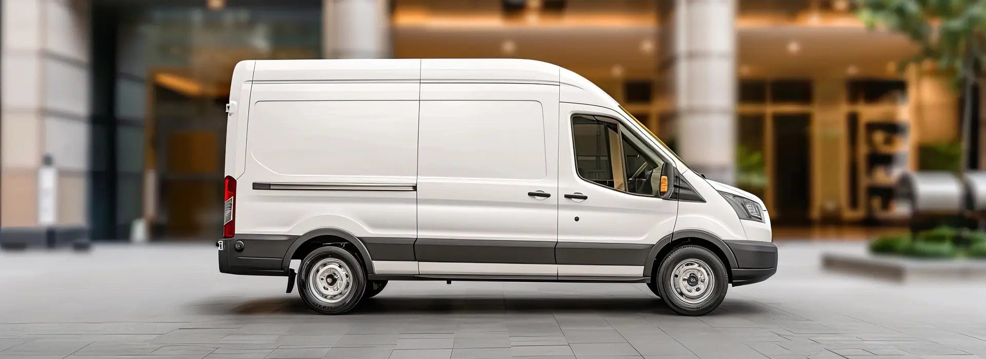 White van in side profile parked outside a modern commercial building
