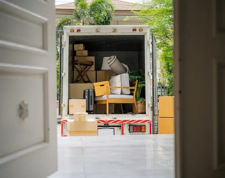 Moving van with open rear doors loaded with furniture, boxes and household items